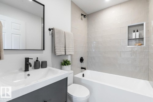 Bathroom featuring a white bathtub with subway tile surround, matte black fixtures, and a recessed shower niche - 4508 109A Avenue, Edmonton, AB - Indoor Photo Showing Bathroom