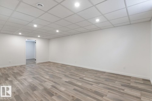 Spacious room featuring wood-finish flooring, white walls, and a dropped ceiling with integrated recessed lighting and a central vent - 4508 109A Avenue, Edmonton, AB - Indoor Photo Showing Other Room