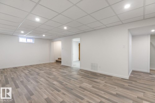 Spacious room featuring wood-finish flooring, recessed lighting, and a drop ceiling - 4508 109A Avenue, Edmonton, AB - Indoor