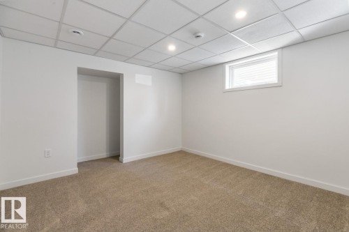 Carpeted room featuring a drop ceiling with recessed lighting, white painted walls, and a single horizontal window - 4508 109A Avenue, Edmonton, AB - Indoor Photo Showing Other Room