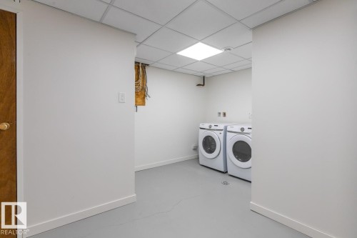 Dedicated laundry area featuring a front-loading washer and dryer set, neutral wall finishes, and a drop ceiling with recessed lighting - 4508 109A Avenue, Edmonton, AB - Indoor Photo Showing Laundry Room