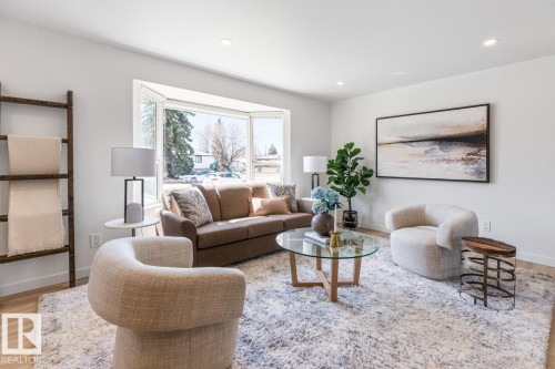 Bright living area featuring a large bay window, recessed lighting, light wood-finish flooring, and crisp white walls - 4508 109A Avenue, Edmonton, AB - Indoor Photo Showing Living Room