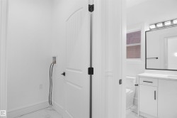 Dedicated laundry area with hookups, featuring white walls, white baseboards, and marble-look tile flooring - 