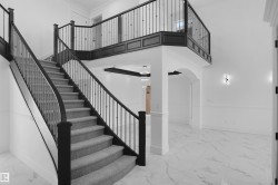 Curved staircase featuring dark wood newel posts and railings with decorative metal balusters, complemented by a carpeted tread - 