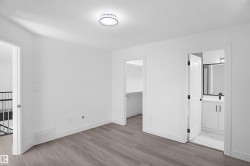 Spacious room featuring wood-finish flooring, white baseboards, and a contemporary ceiling fixture - 
