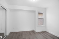 Bedroom featuring wood-finish flooring, white baseboards, a white window frame, and a built-in closet with mirrored sliding doors - 