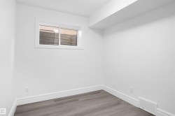 Finished interior space with wood-finish flooring, white walls, and a window - 