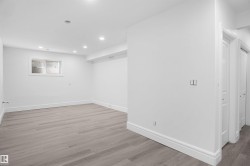 Spacious room featuring wood-finish flooring, recessed lighting, a horizontal window with blinds, and multiple paneled doors - 