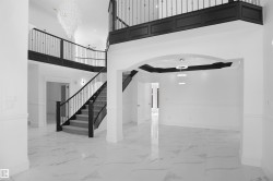Grand entryway featuring a sweeping staircase with dark wood newel posts and balusters, plush carpeted treads, and an upper-level balcony - 