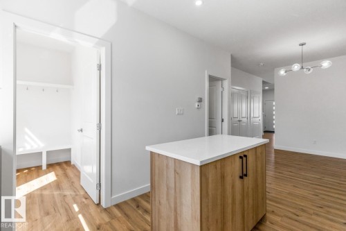 Kitchen island with a white countertop and wood-finish cabinetry - 6625 46 Avenue, Beaumont, AB - Indoor Photo Showing Other Room
