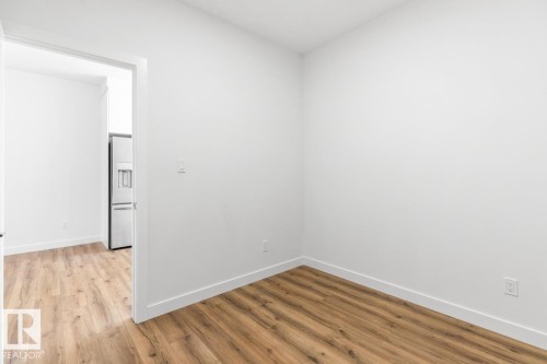 Room featuring light wood-finish flooring and bright white walls - 6625 46 Avenue, Beaumont, AB - Indoor Photo Showing Other Room