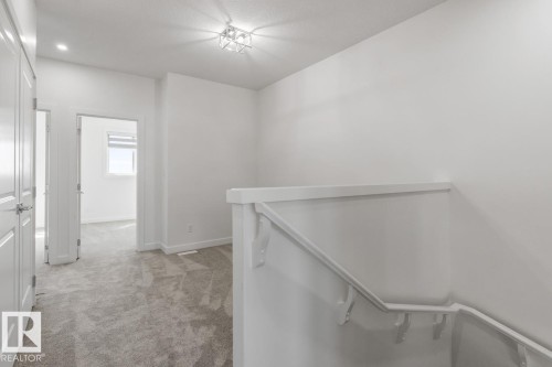 Upper landing featuring light gray patterned carpeting, white walls, and a contemporary ceiling light fixture - 6625 46 Avenue, Beaumont, AB - Indoor Photo Showing Other Room