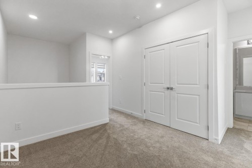 Carpeted landing area featuring a half-wall partition, recessed lighting, and a double-door closet with satin nickel hardware - 6625 46 Avenue, Beaumont, AB - Indoor Photo Showing Other Room