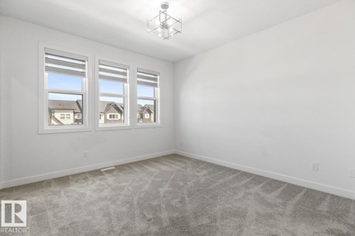 White painted walls and gray patterned carpet create a neutral aesthetic - 6625 46 Avenue, Beaumont, AB - Indoor Photo Showing Other Room