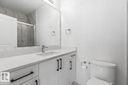 Modern bathroom featuring a vanity with a white quartz countertop, integrated rectangular sink, and matte black hardware - 6625 46 Avenue, Beaumont, AB - Indoor Photo Showing Bathroom