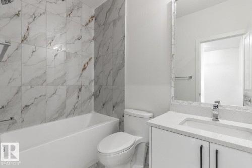 Bathroom featuring a white vanity with a light-toned countertop, an integrated sink, and modern black hardware - 6625 46 Avenue, Beaumont, AB - Indoor Photo Showing Bathroom