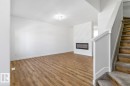Open-concept living space with wood-finish flooring, a contemporary electric fireplace with a diagonal shiplap accent wall, a white painted staircase with carpeted treads, and a flush-mount ceiling light fixture - 6625 46 Avenue, Beaumont, AB  - Indoor Photo Showing Other Room 