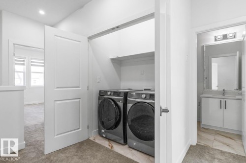 Dedicated laundry closet featuring a stacked washer and dryer, overhead shelving, and a tiled floor - 6625 46 Avenue, Beaumont, AB - Indoor Photo Showing Laundry Room