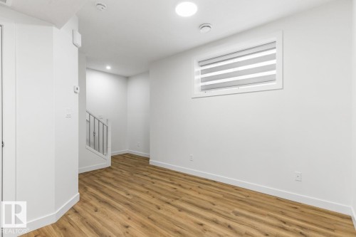 Bright interior space featuring wood-finish flooring, white walls, and contemporary baseboards - 6625 46 Avenue, Beaumont, AB - Indoor Photo Showing Other Room