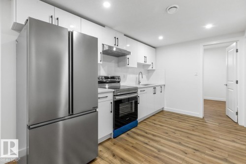 Kitchen featuring stainless steel appliances, white cabinetry, wood-finish flooring, recessed lighting, and a white subway tile backsplash - 6625 46 Avenue, Beaumont, AB - Indoor Photo Showing Kitchen