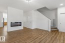 Living area featuring wood-finish flooring, an electric fireplace with a shiplap accent wall, and a staircase with carpeted treads - 6625 46 Avenue, Beaumont, AB  - Indoor With Fireplace 