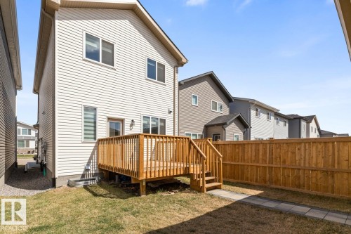 Rear exterior featuring a wooden deck with railing and stairs, white vinyl siding, multiple windows, and a wooden privacy fence - 6625 46 Avenue, Beaumont, AB - Outdoor With Deck Patio Veranda With Exterior