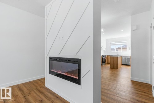 Electric fireplace with shiplap accent wall, wood-finish flooring, and recessed lighting - 6625 46 Avenue, Beaumont, AB - Indoor