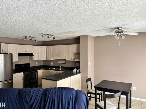 This property features a kitchen with light-colored cabinetry, dark countertops, and stainless steel appliances, including a refrigerator and range - 11904 18 Avenue, Edmonton, AB - Indoor Photo Showing Kitchen With Double Sink
