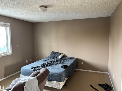 This room features neutral-toned walls, a window providing natural light, and a ceiling light fixture - 11904 18 Avenue, Edmonton, AB - Indoor Photo Showing Bedroom