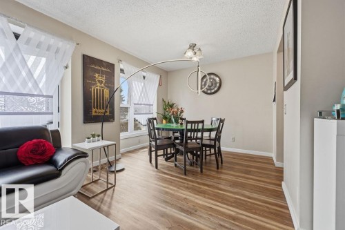 Open-concept living and dining area featuring wood-finish flooring, neutral wall paint, and multiple windows - 7422 188 Street, Edmonton, AB - Indoor
