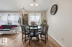Dining area with wood-finish flooring and a contemporary circular pendant light fixture - 