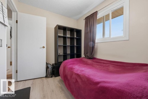 Bedroom featuring wood-finish flooring, a white-framed window, and a built-in black shelving unit - 7422 188 Street, Edmonton, AB - Indoor Photo Showing Bedroom