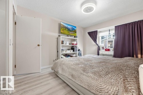 Light wood-finish flooring complements neutral wall tones and a textured ceiling - 7422 188 Street, Edmonton, AB - Indoor Photo Showing Bedroom