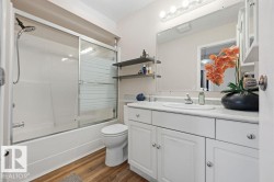 Bathroom featuring a white vanity with integrated sink, a large wall-mounted mirror, and a combination bathtub and shower with sliding glass doors - 
