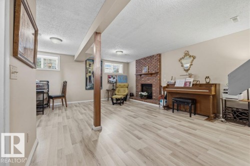 Spacious room featuring light wood-finish flooring, a brick fireplace with a wood mantel, and overhead recessed lighting - 7422 188 Street, Edmonton, AB - Indoor With Fireplace