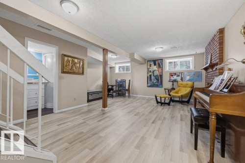 Spacious lower level featuring wood-finish flooring, recessed lighting, and a visible brick accent wall - 7422 188 Street, Edmonton, AB - Indoor