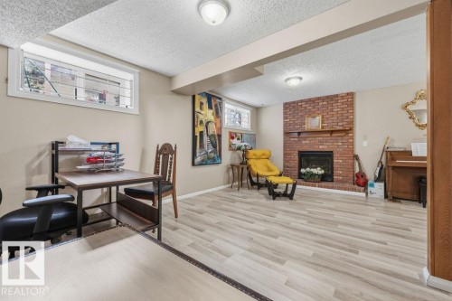 Finished space featuring light wood-finish flooring, a brick fireplace with a wood mantle, recessed windows with security bars, and ceiling-mounted lighting - 7422 188 Street, Edmonton, AB - Indoor With Fireplace