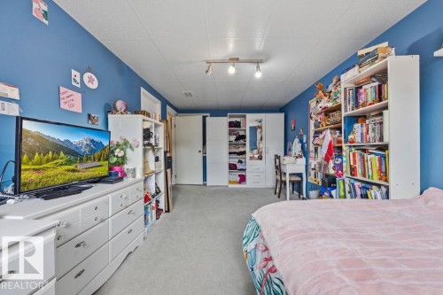 Spacious room featuring blue painted walls, light gray carpeting, and a white ceiling with track lighting - 7422 188 Street, Edmonton, AB - Indoor Photo Showing Bedroom