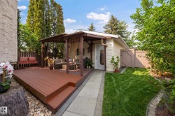 Spacious backyard featuring a multi-tiered deck, covered patio structure, lush lawn, mature perimeter trees, and a detached auxiliary building - 