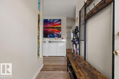 Entryway featuring wood-finish flooring, a contemporary storage cabinet, and a stained-glass window panel - 7422 188 Street, Edmonton, AB - Indoor Photo Showing Other Room