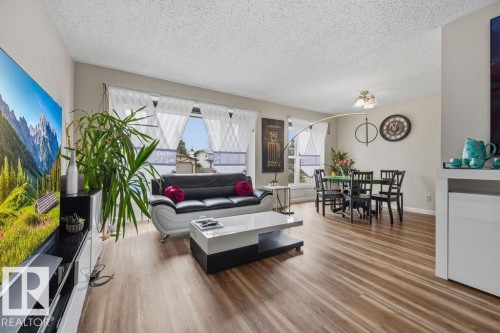 Open-concept living area featuring wood-finish flooring, neutral wall tones, and multiple windows with white window treatments - 7422 188 Street, Edmonton, AB - Indoor Photo Showing Living Room