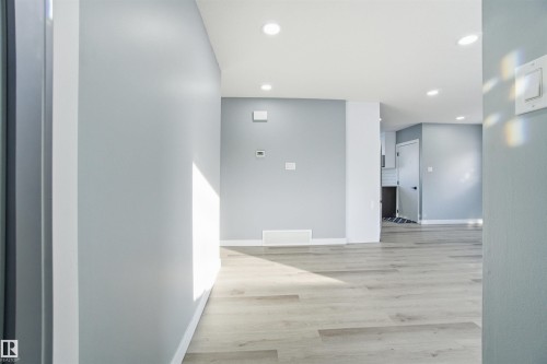 The property features light-colored plank flooring and recessed lighting, with walls painted in a light blue shade - 5208 90 Avenue, Edmonton, AB - Indoor Photo Showing Other Room