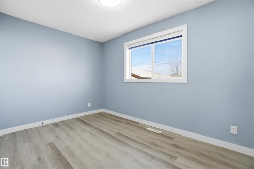 The room features light blue walls, a window providing natural light, and light-toned flooring - 5208 90 Avenue, Edmonton, AB - Indoor Photo Showing Other Room