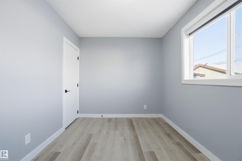 This room features light-colored walls, a window providing natural light, and light wood-style flooring - 5208 90 Avenue, Edmonton, AB - Indoor Photo Showing Other Room
