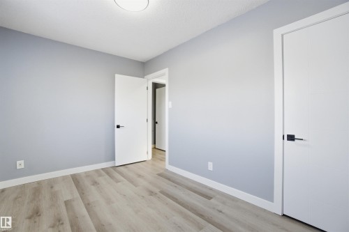This property features light-colored flooring, light gray walls, and white trim - 5208 90 Avenue, Edmonton, AB - Indoor Photo Showing Other Room