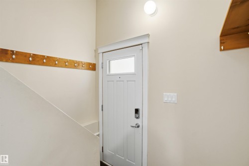 The entryway features a white door with a window, a modern light fixture, and a wooden shelf - 5208 90 Avenue, Edmonton, AB - Indoor Photo Showing Other Room