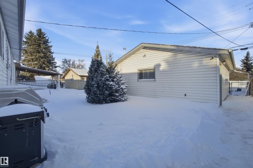 The property features a spacious yard with mature trees and a detached garage with horizontal siding and a window - 5208 90 Avenue, Edmonton, AB - Outdoor With Exterior