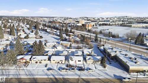 An aerial view of the community, featuring numerous detached properties, paved roads, and a commercial building - 5208 90 Avenue, Edmonton, AB - Outdoor With Body Of Water With View