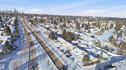 Aerial view of the neighbourhood featuring snow-covered rooftops and trees, with a distant cityscape visible on the horizon - 5208 90 Avenue, Edmonton, AB - Outdoor With View