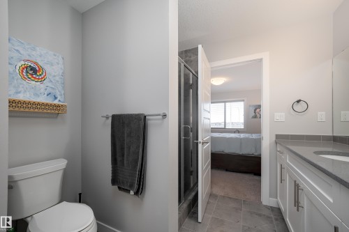 Bathroom featuring a white toilet, a shower enclosure with a glass door, a vanity with white cabinetry, a gray countertop, and a built-in sink - 2704 Koshal Place, Edmonton, AB - Indoor Photo Showing Bathroom